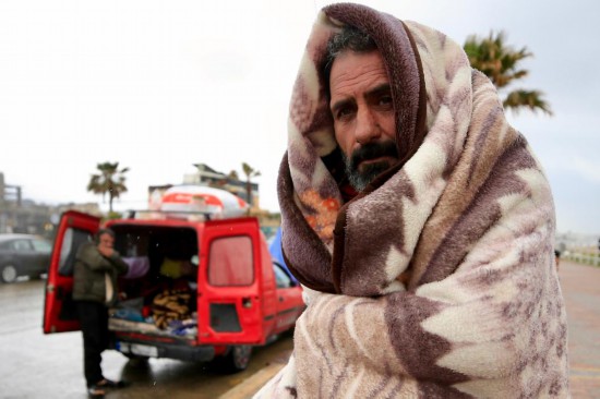 　　3月15日，在黎巴嫩南部赛达市附近的一条公路旁，一名黎巴嫩流离失所者用毯子御寒。新华社发（阿里·哈希绍摄）